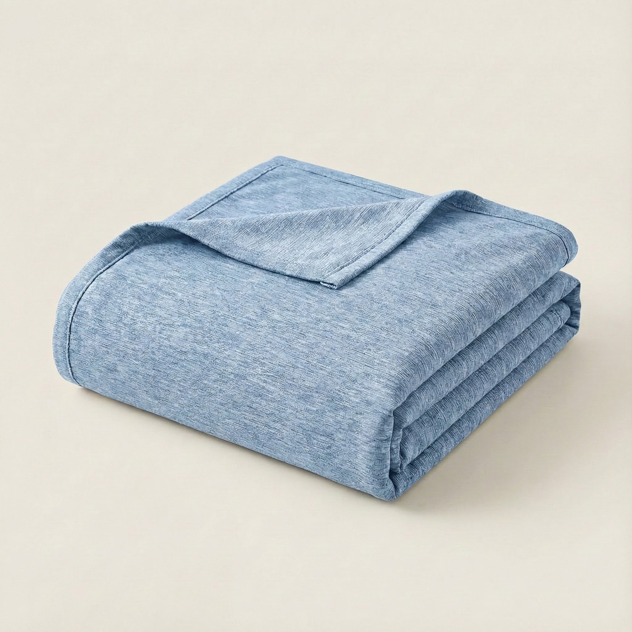 Folded light blue blanket on a beige background