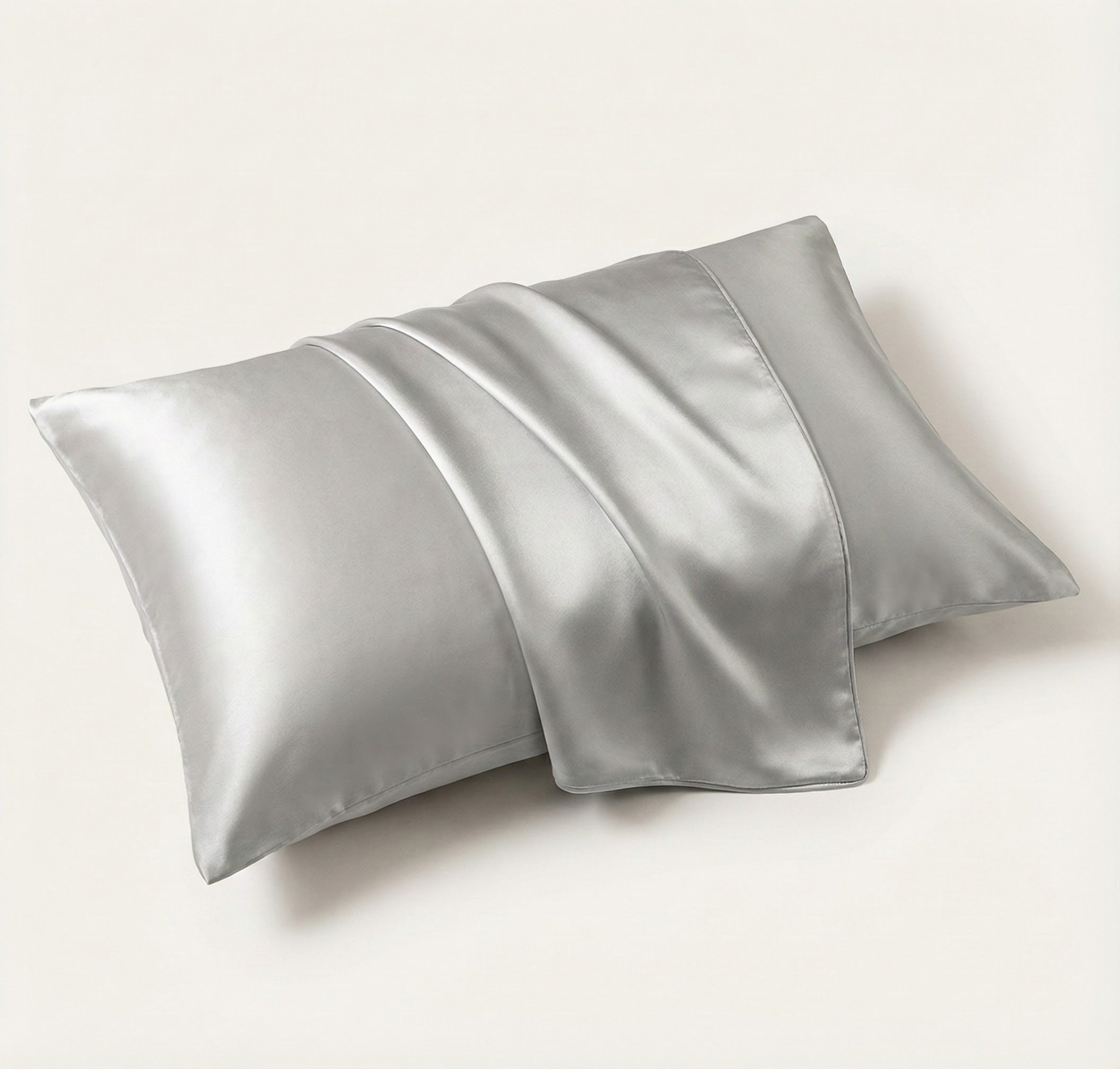 Two silver satin pillowcases on a white background