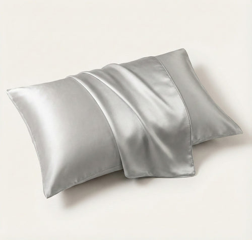 Two silver satin pillowcases on a white background