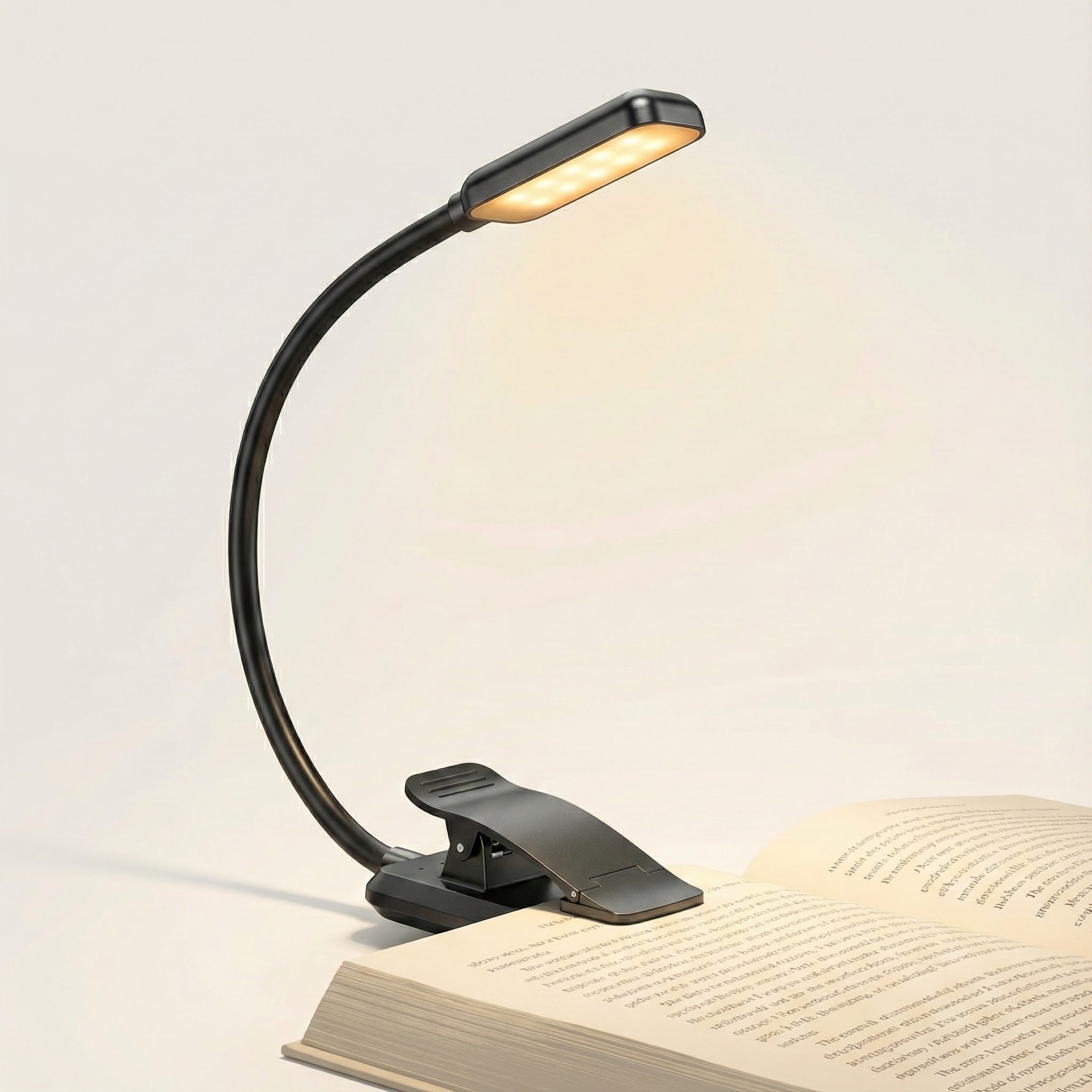 Black adjustable reading lamp on an open book with a plain background
