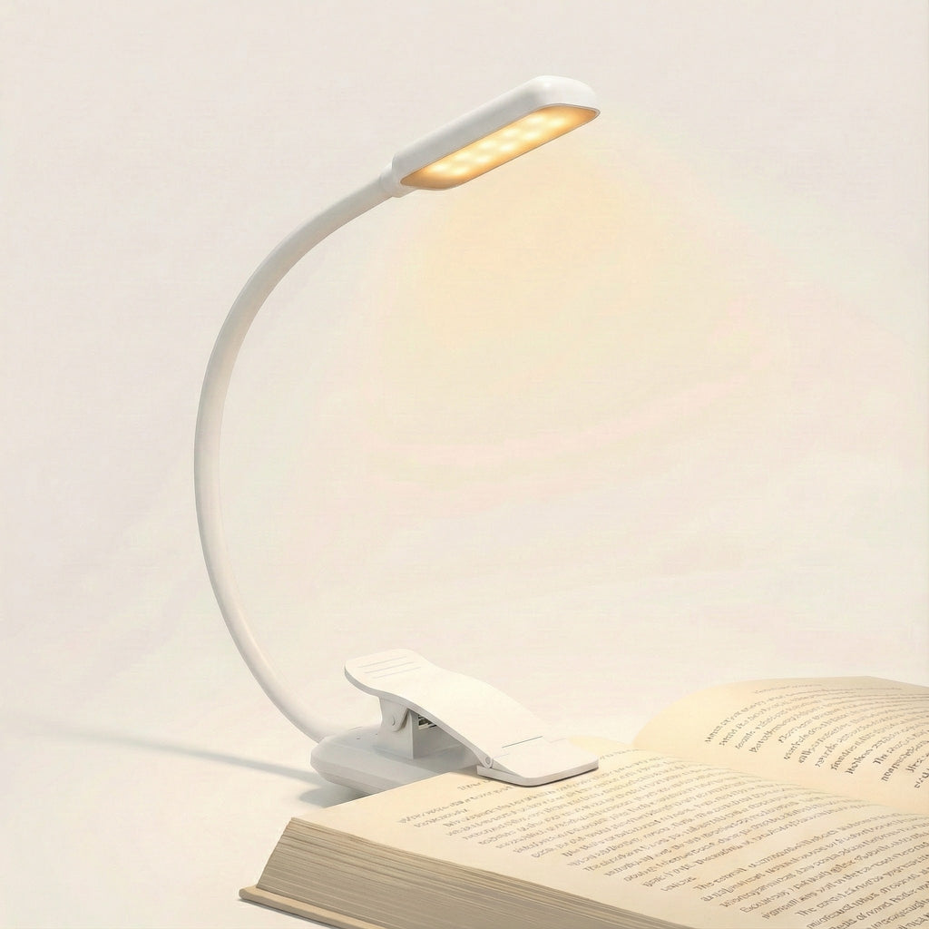 White LED reading lamp with clip on an open book against a light background