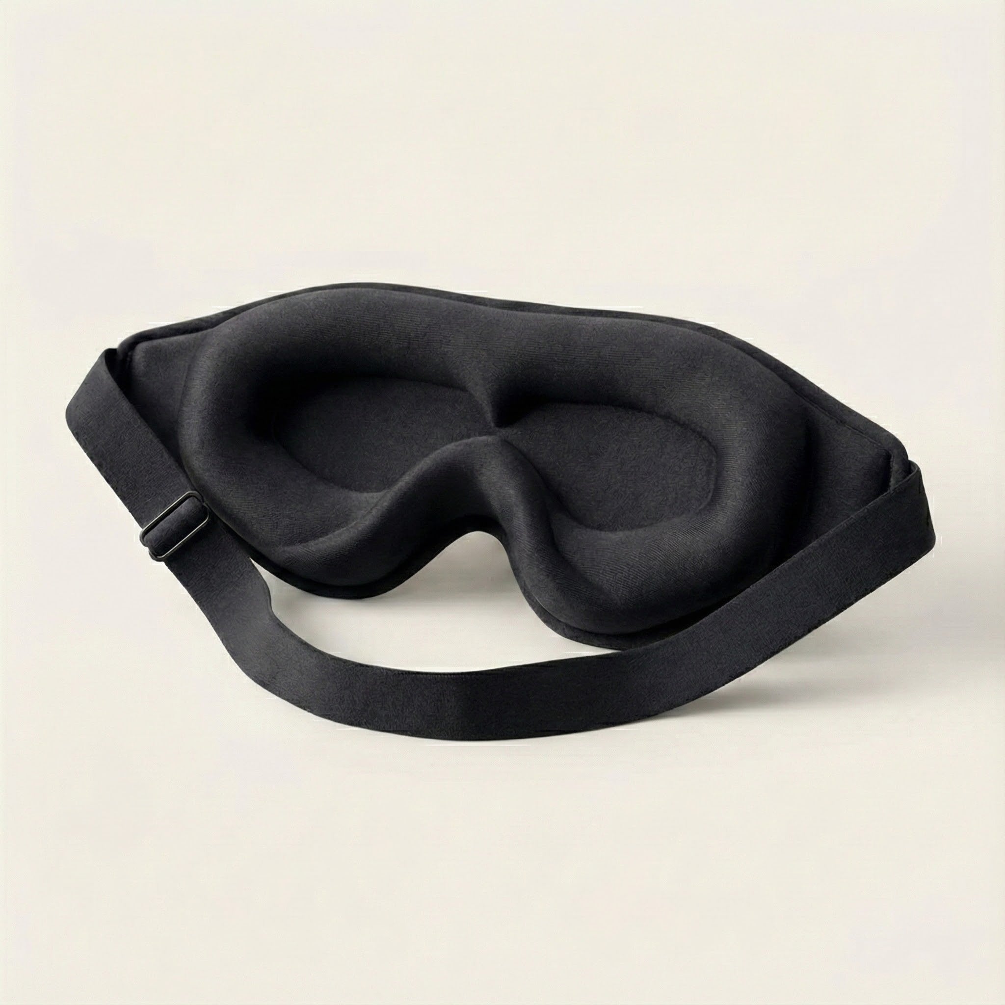 Black sleep mask on a light beige background